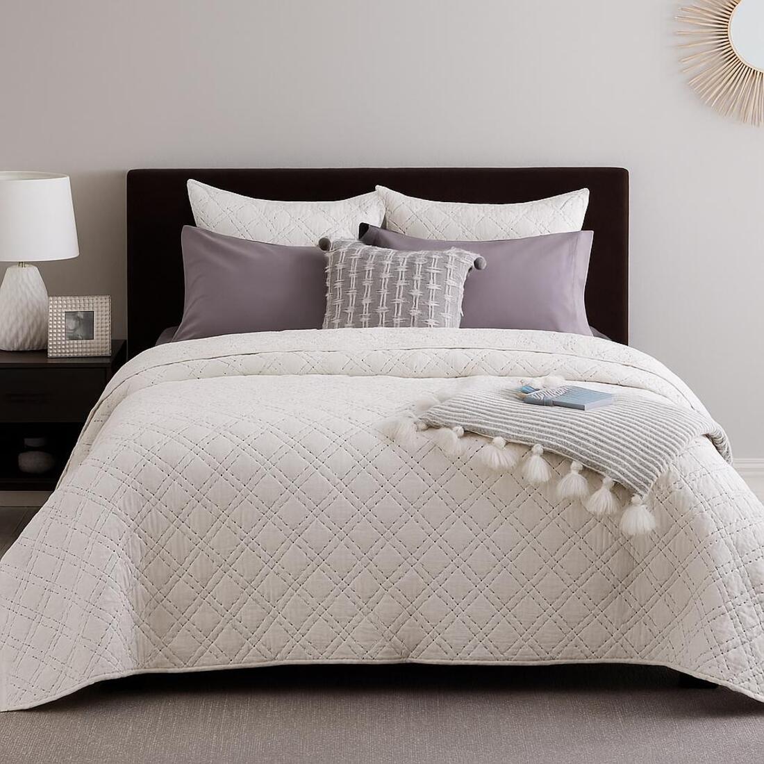 Neatly made bed with a quilt and pillows in a bedroom setting.