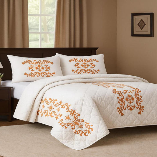 White quilt with orange floral patterns on a bed in a bedroom setting.