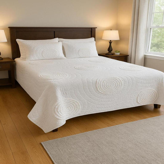Bedroom with a bed covered in a white quilt and pillows, wooden headboard, and lamps on nightstands.
