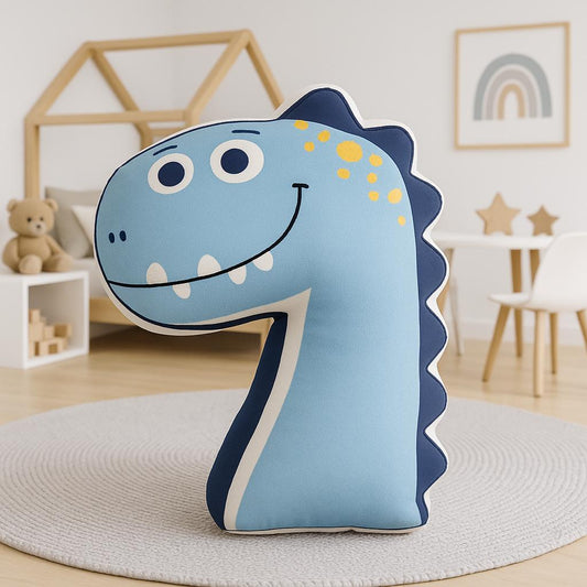 Blue dinosaur-shaped pillow on a round rug in a room with a teddy bear and rainbow decorations.