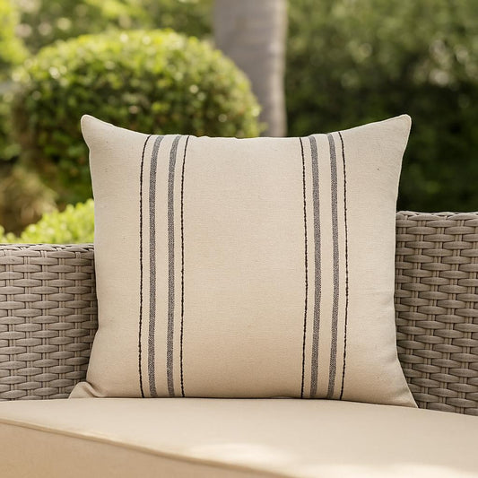 Beige pillow with black stripes on a wicker chair outdoors