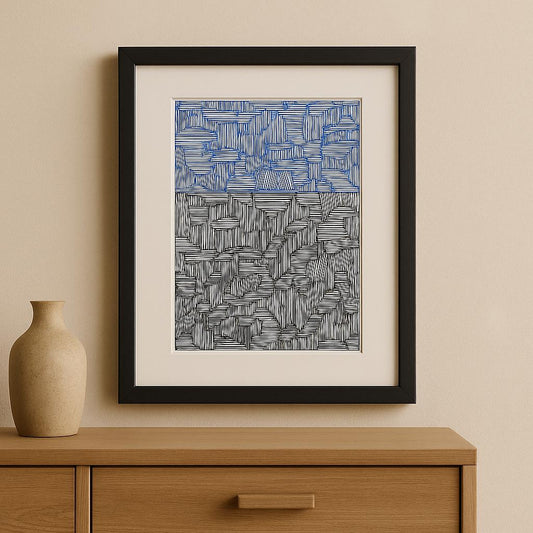 Framed abstract artwork with blue and gray patterns on a beige wall above a wooden cabinet.