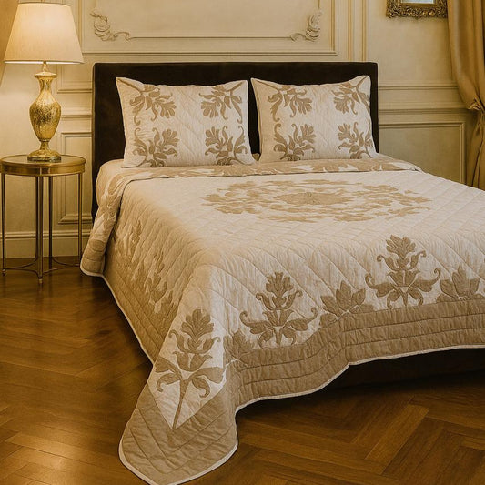 Decorative bedspread with floral patterns on a bed in a room with a lamp and side table.