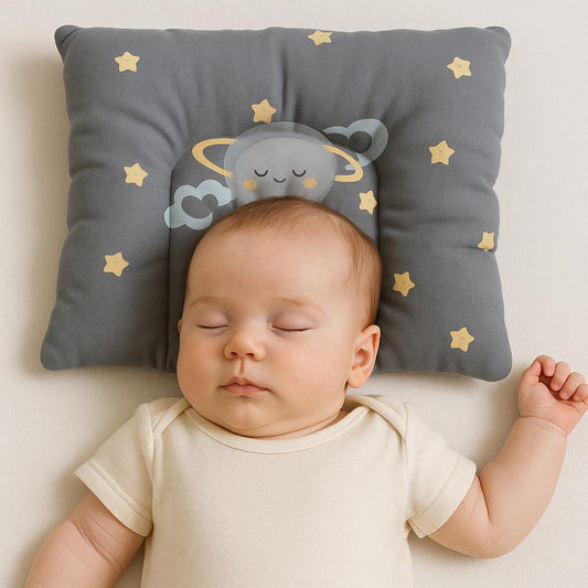 Baby lying on a soft surface with a decorative pillow featuring cartoon characters and stars.
