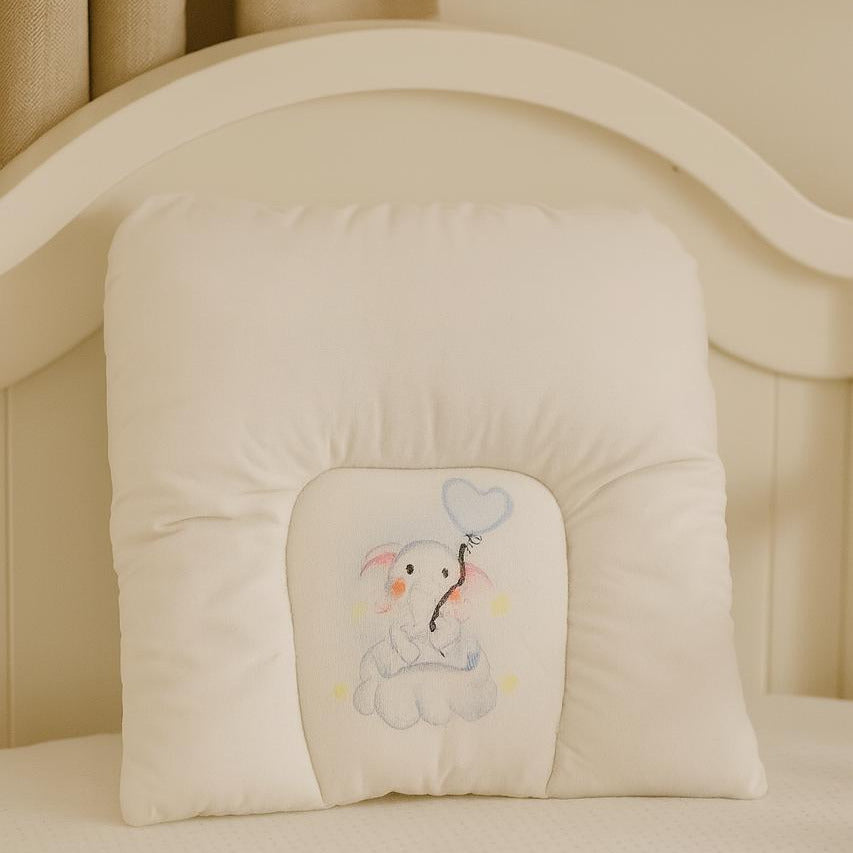 Beige baby crib bumper with embroidered design of a bear holding a heart-shaped balloon.