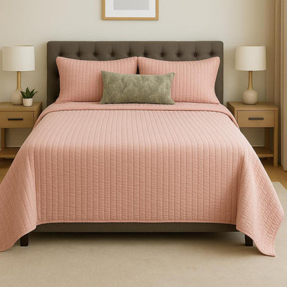 Bed with pink quilt and pillows in a bedroom setting