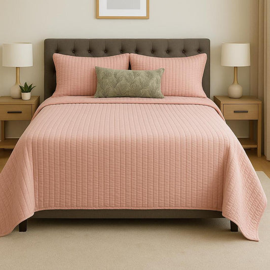 Bed with pink quilt and pillows in a bedroom setting