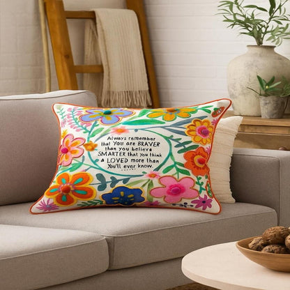 Decorative pillow with floral design and motivational quote on a couch in a living room setting.