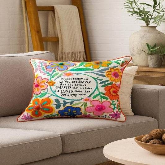 Decorative pillow with floral design and motivational quote on a couch in a living room setting.