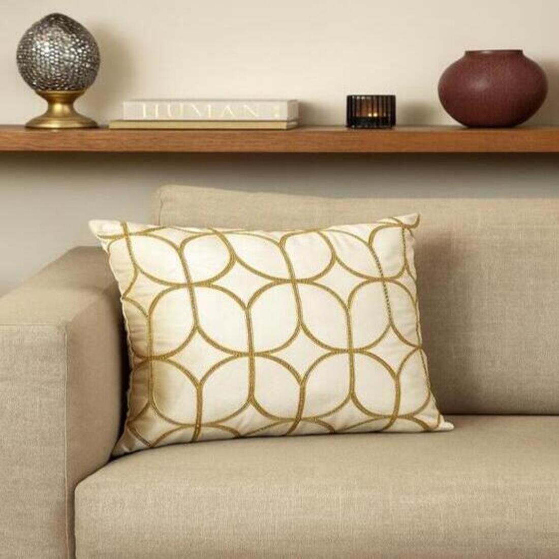 Decorative pillow on a beige sofa with a shelf in the background