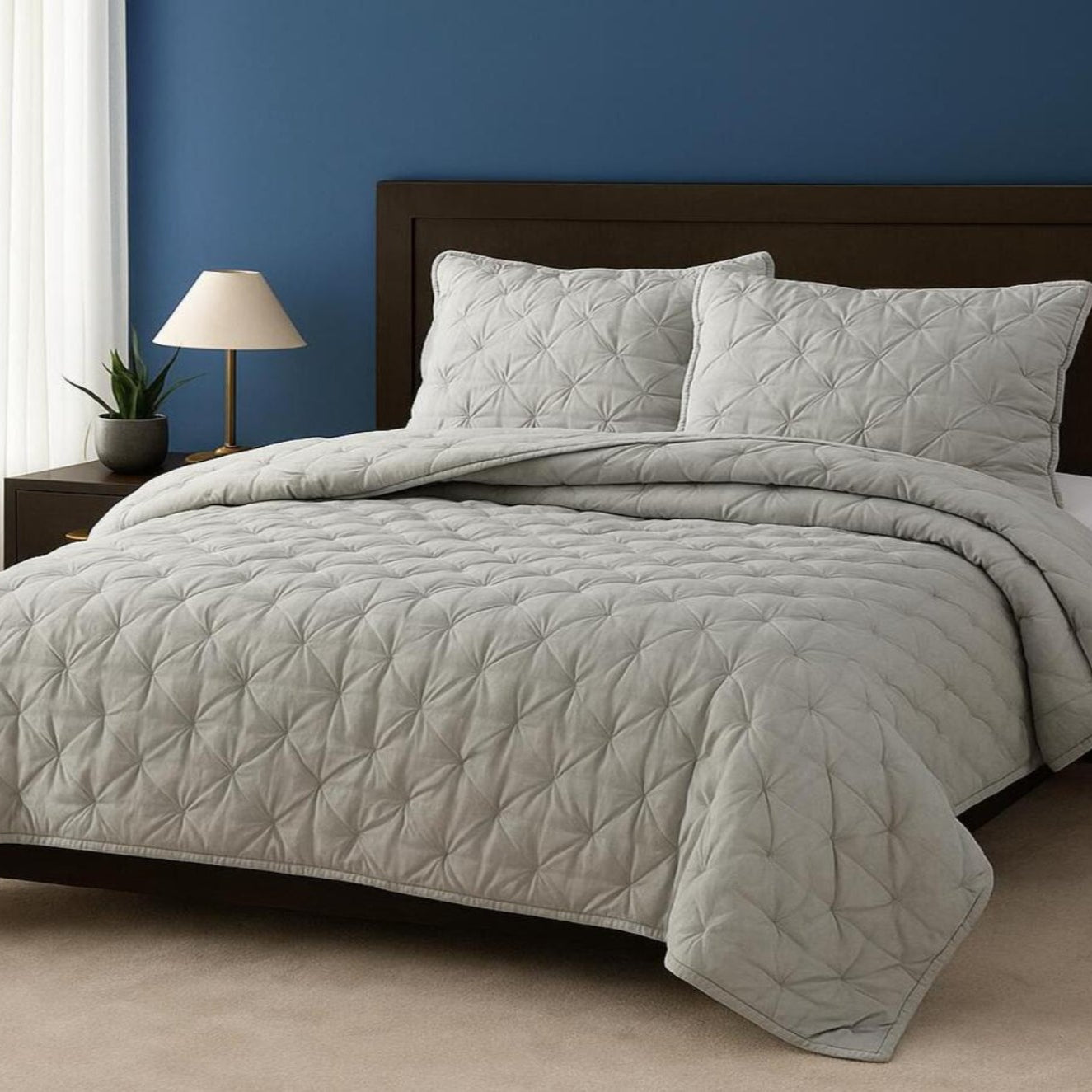 Quilted gray comforter set on a bed with a dark wooden headboard against a blue wall.