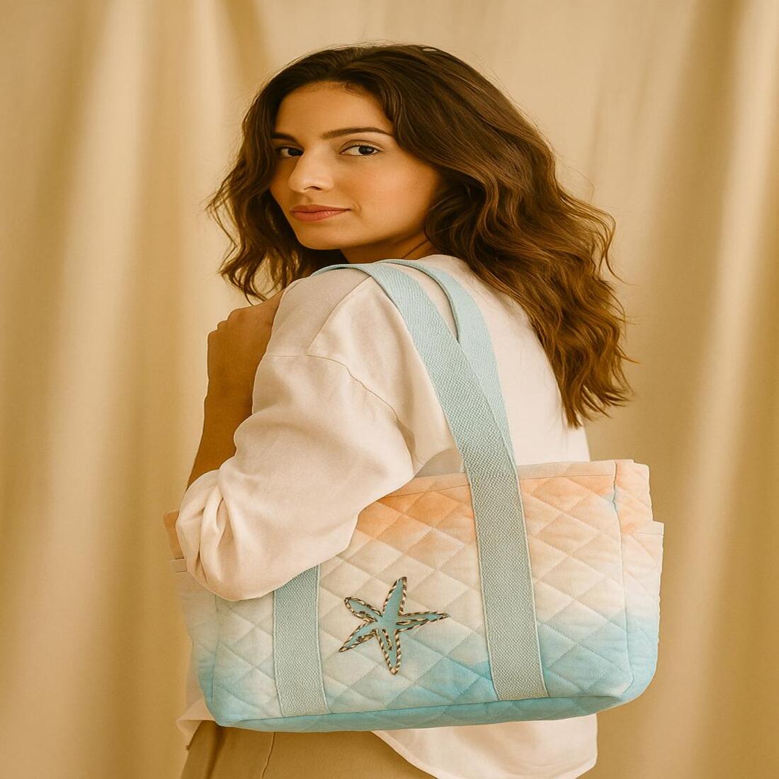 Woman holding a quilted handbag with a starfish design against a beige background