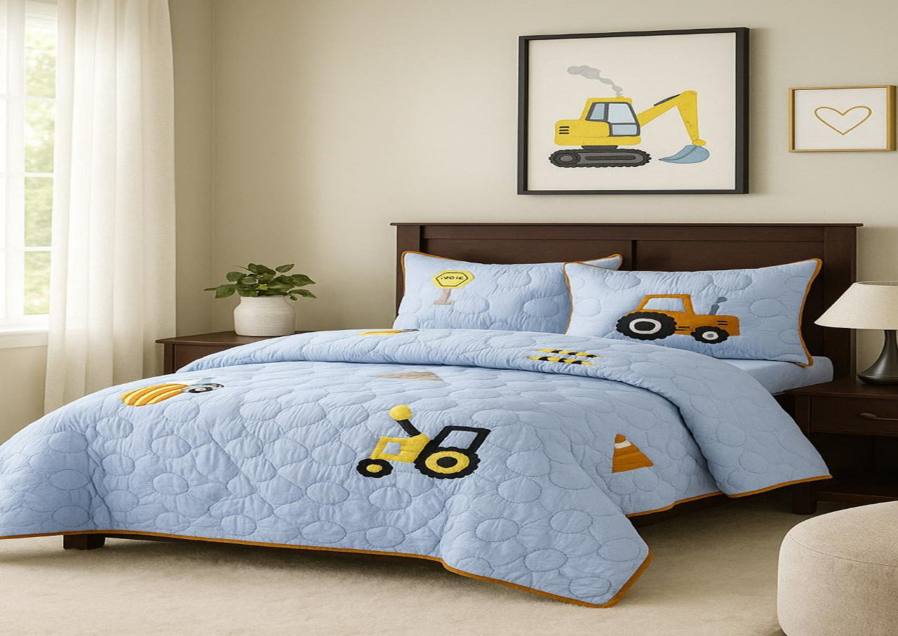 Children's bedroom with blue quilt set featuring construction vehicle designs.