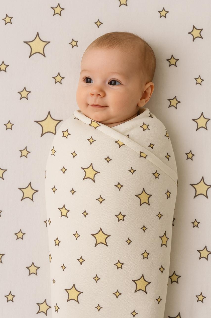Baby wrapped in a blanket with star pattern against a star-patterned wall