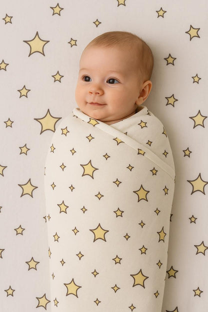 Baby wrapped in a blanket with star pattern against a star-patterned wall