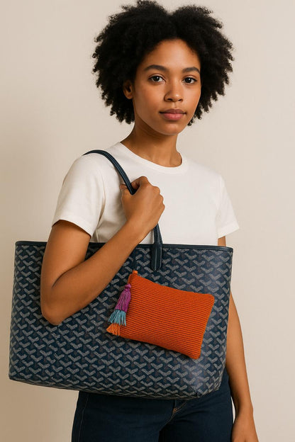 Person holding a large tote bag with an orange pouch on a beige background