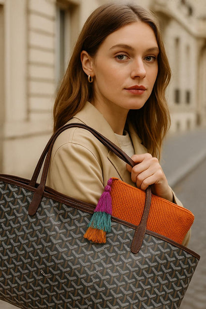 Woman holding a patterned handbag with colorful tassels outdoors.