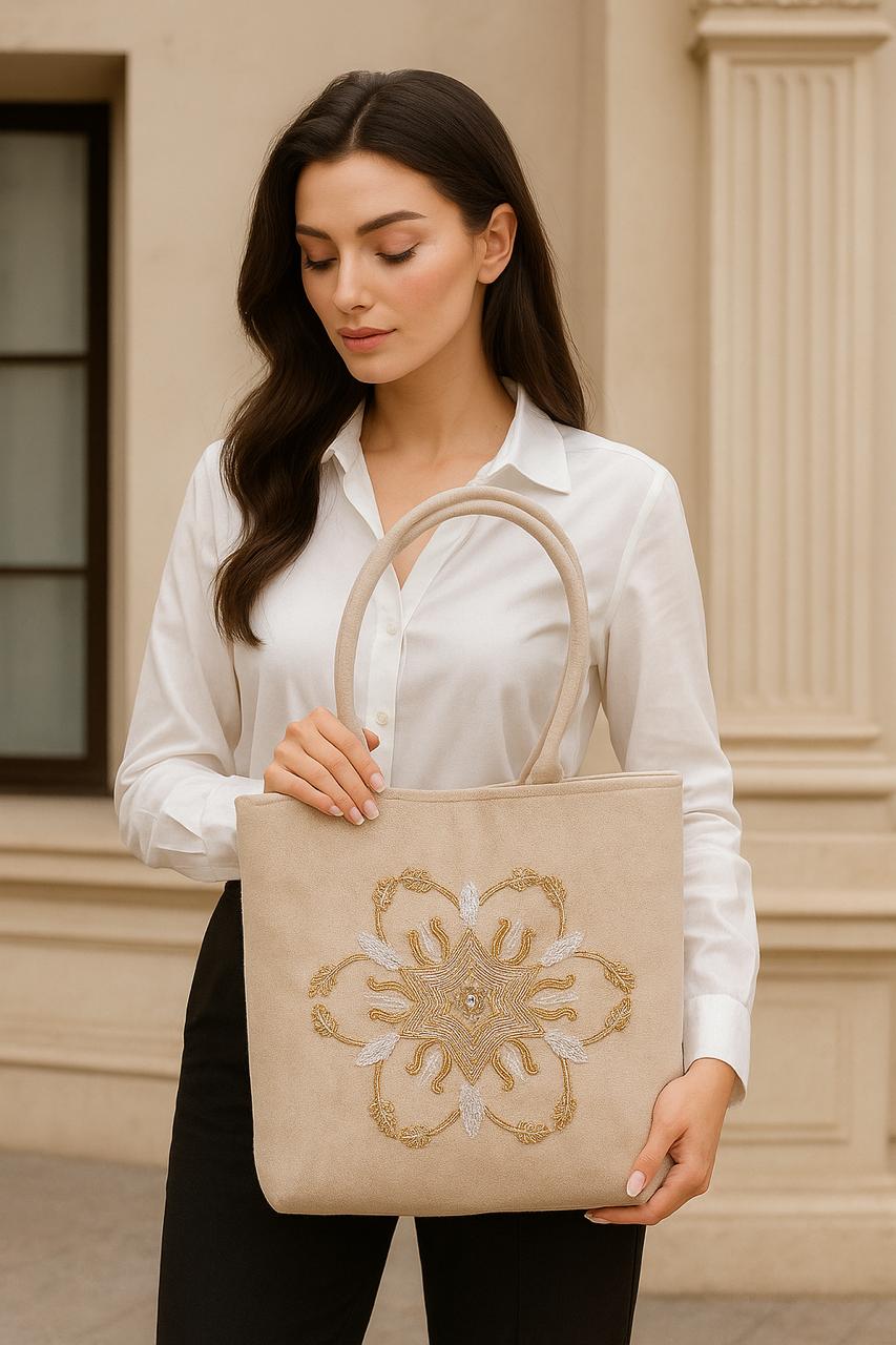 Woman holding a beige tote bag with decorative elements against a beige building background