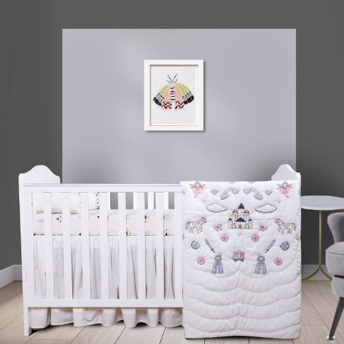 A baby quilt with a whimsical design featuring unicorns, castles, and other fairy-tale elements, displayed on a crib in a nursery room.