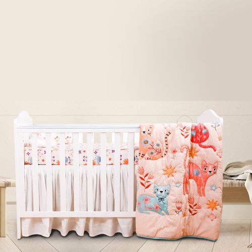 A baby crib set with a quilt featuring cartoon cats, a fitted sheet, and a baby pillow, displayed in a room setting.