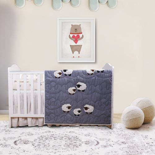 A baby quilt with a sheep design displayed on a crib in a nursery room.