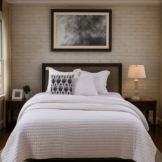 Neatly made bed with white bedding and decorative pillows in a bedroom setting.